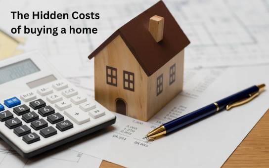  An image showing a table with a toy house, calculator, papers and pen. There is a title on the page and it is The Hidden Costs of Buying a Home.